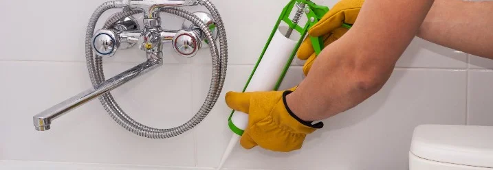 Person verwendet Dichtmittel in Badewanne